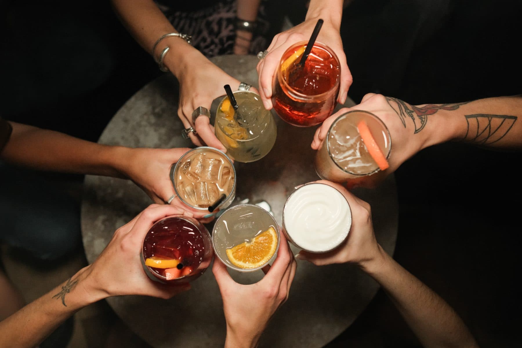 Six glasses raised over a table — a round of cocktails at Cabana