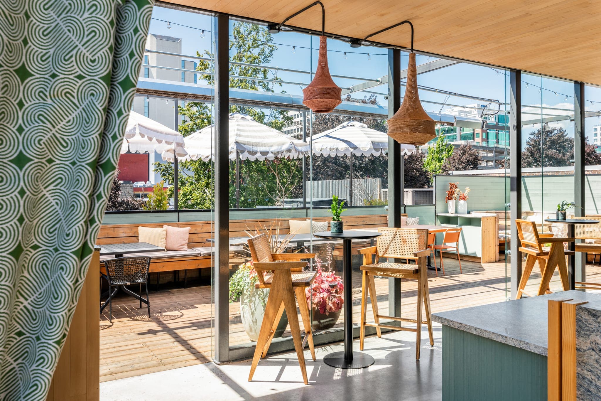 One of the two rooftop patios — covered bar seating looking out to umbrellas and greenery